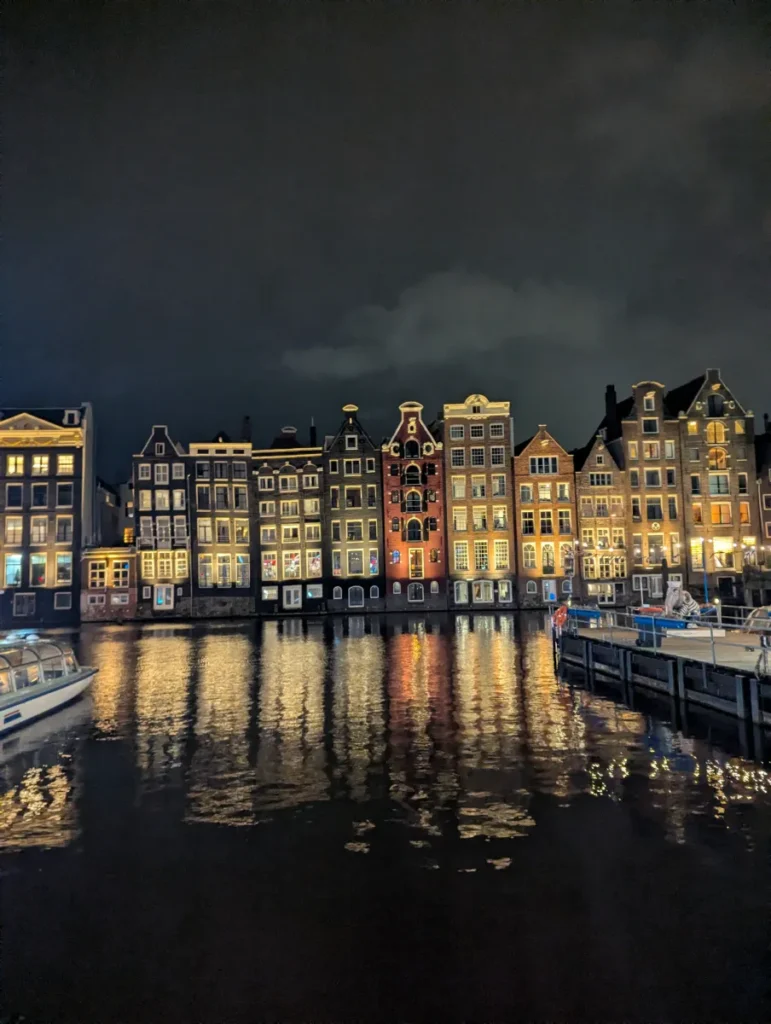 row of historic houses in amsterdam canal illuminated at night