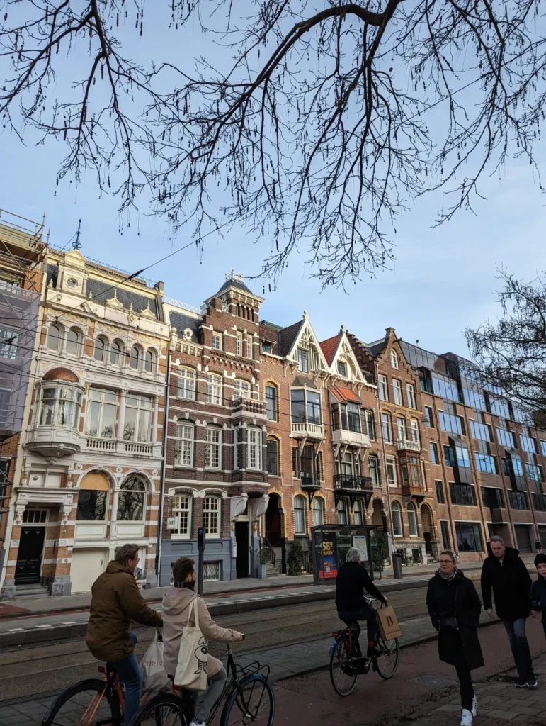 busy street of amsterdam is filled with bikes and pedestrians