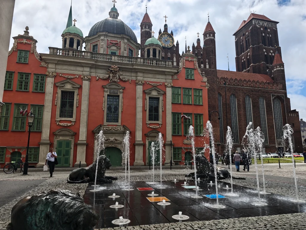 fountains the square in front of the iconic colorful small Catholic church of Gdansk, in front of the gothic cathedral  
