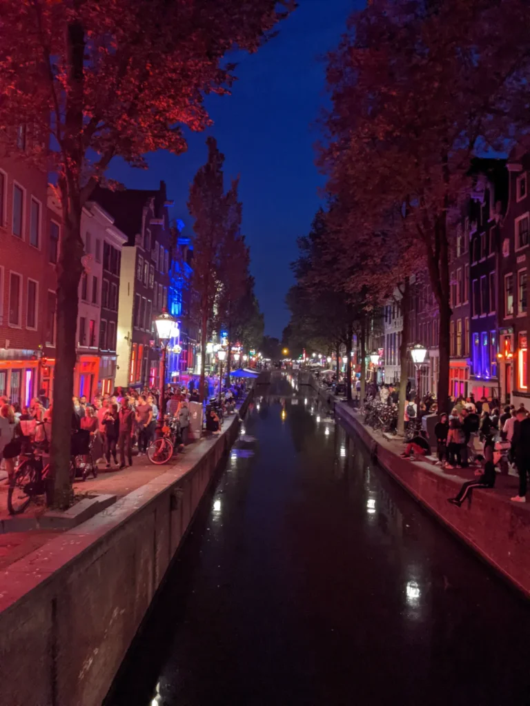 crowd gathering in the narrow historic alleyways of De Wallen, Amsterdam's Red Light District
